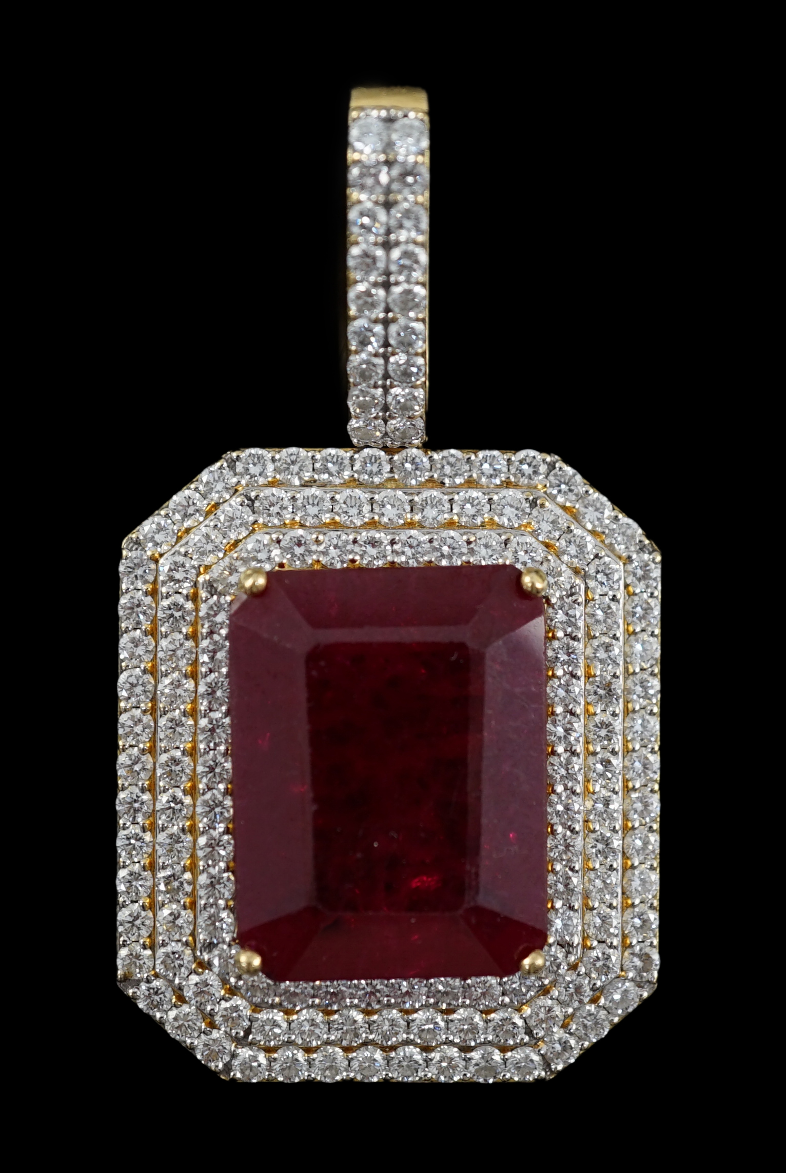 A large modern 18ct gold and single emerald cut synthetic ruby set pendant, bordered by three concentric bands of round brilliant cut diamonds